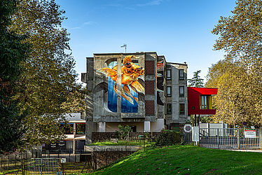 Au milieu d'arbres lesimmeubles d'une résidence. Sur l'une des façades, un poisson japonais est représenté sur toutes la hauteur.